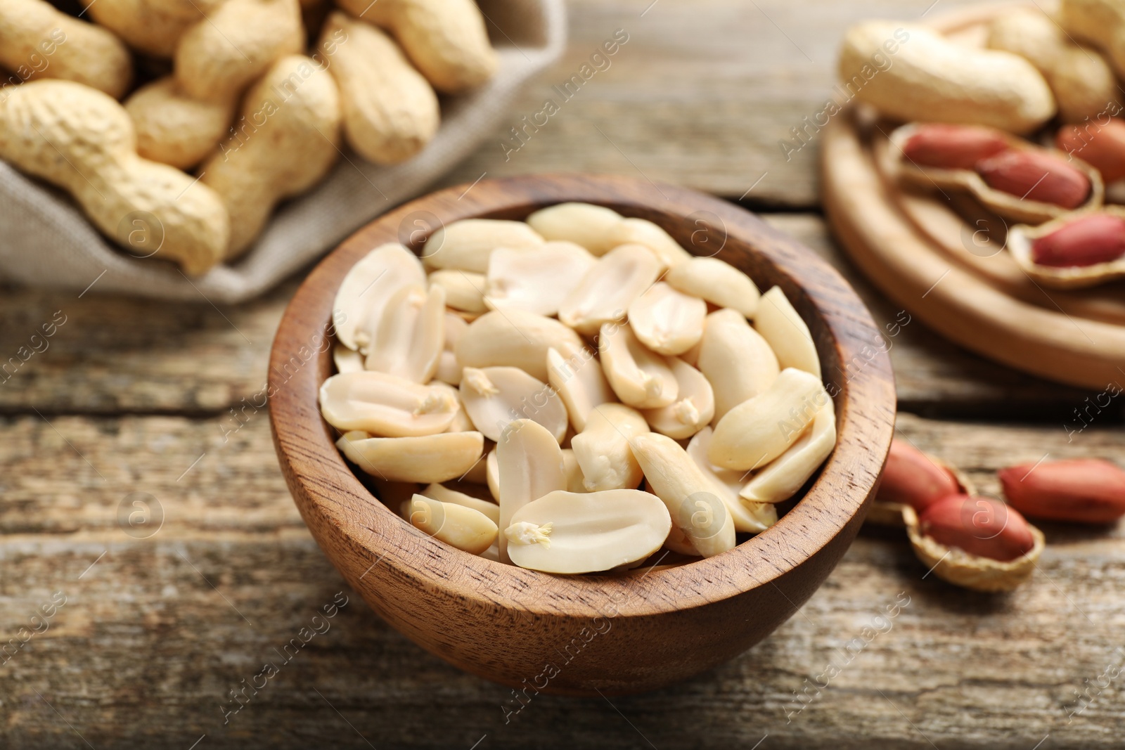 Photo of Fresh peanuts in bowl on wooden table, closeup