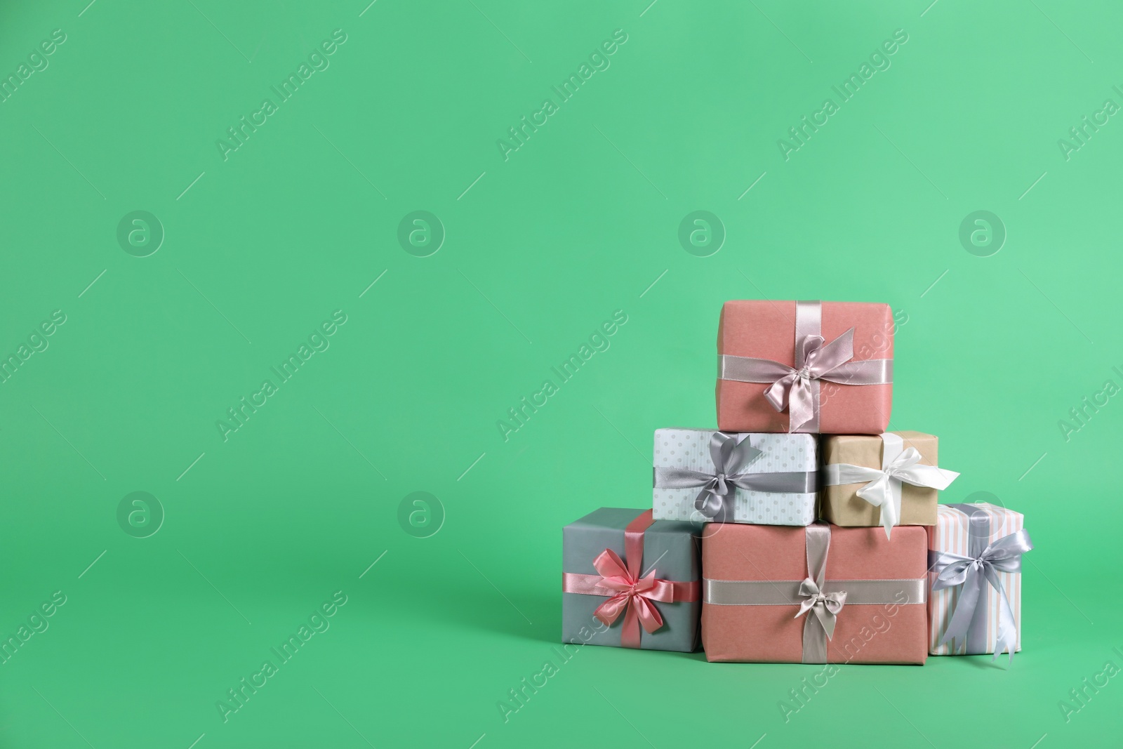 Photo of Many beautifully wrapped gift boxes on green background. Space for text