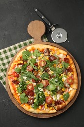 Photo of Delicious vegetarian pizza and cutter on black table, top view