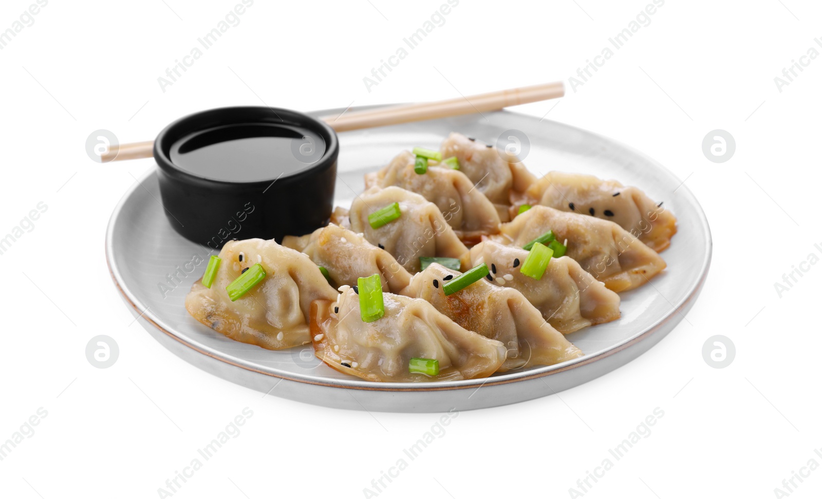 Photo of Delicious gyoza (asian dumplings) with green onions, soy sauce and chopsticks isolated on white