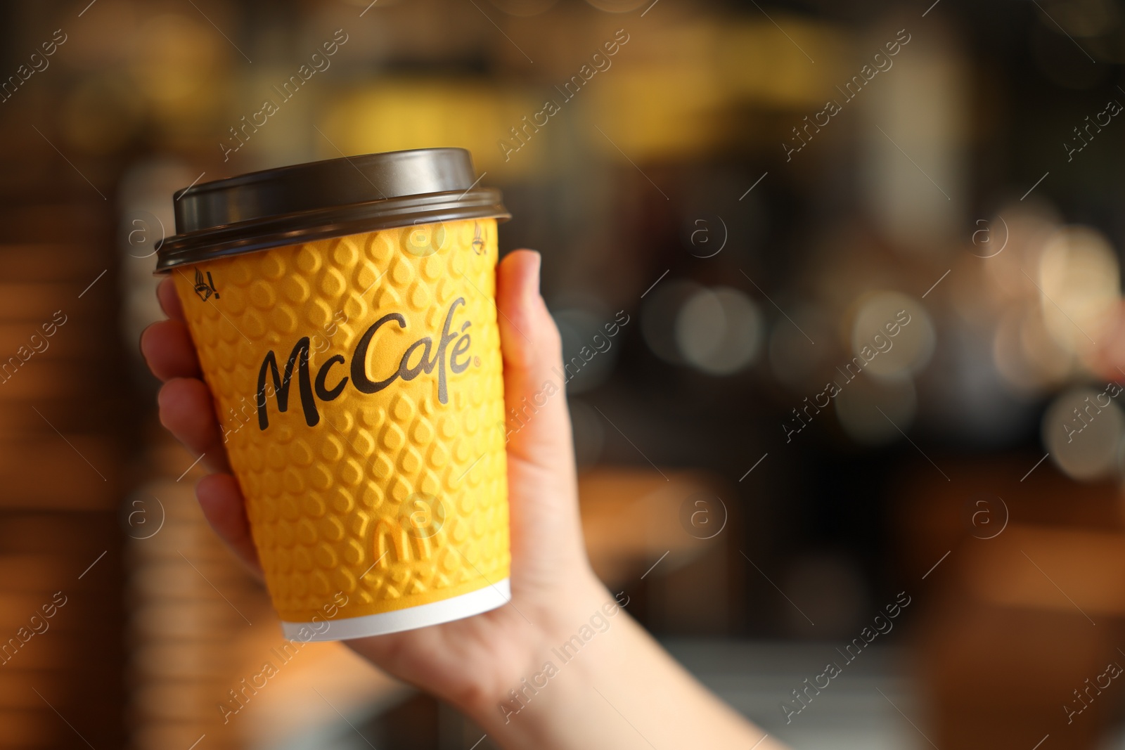 Photo of Lviv, Ukraine - September 26, 2023: Woman with hot McDonald's drink in cafe, closeup. Space for text