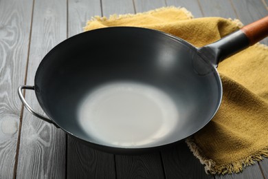 Empty iron wok and napkin on grey wooden table