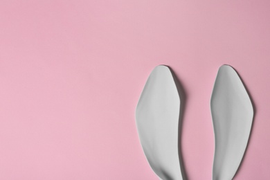 Photo of Funny Easter bunny ears on color background, top view with space for text