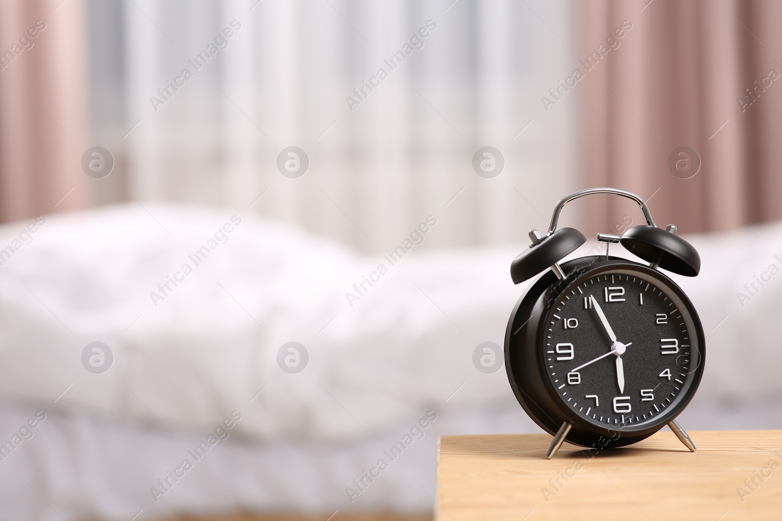 Photo of Black alarm clock on wooden table indoors. Space for text