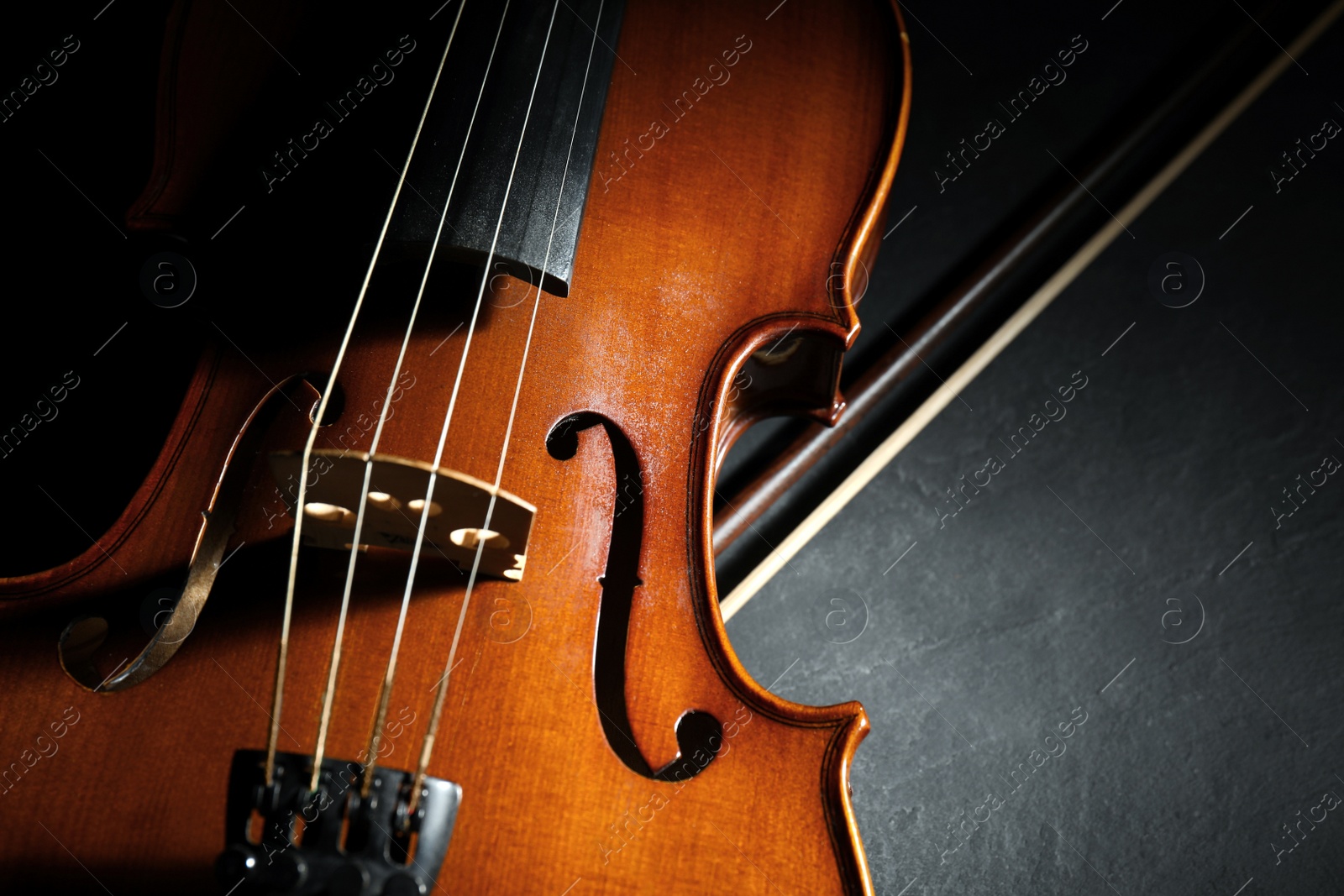 Photo of Classic violin and bow on stone table, closeup