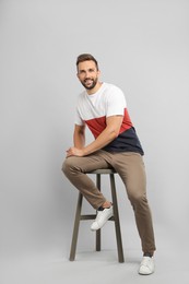 Photo of Handsome man sitting on stool against light grey background