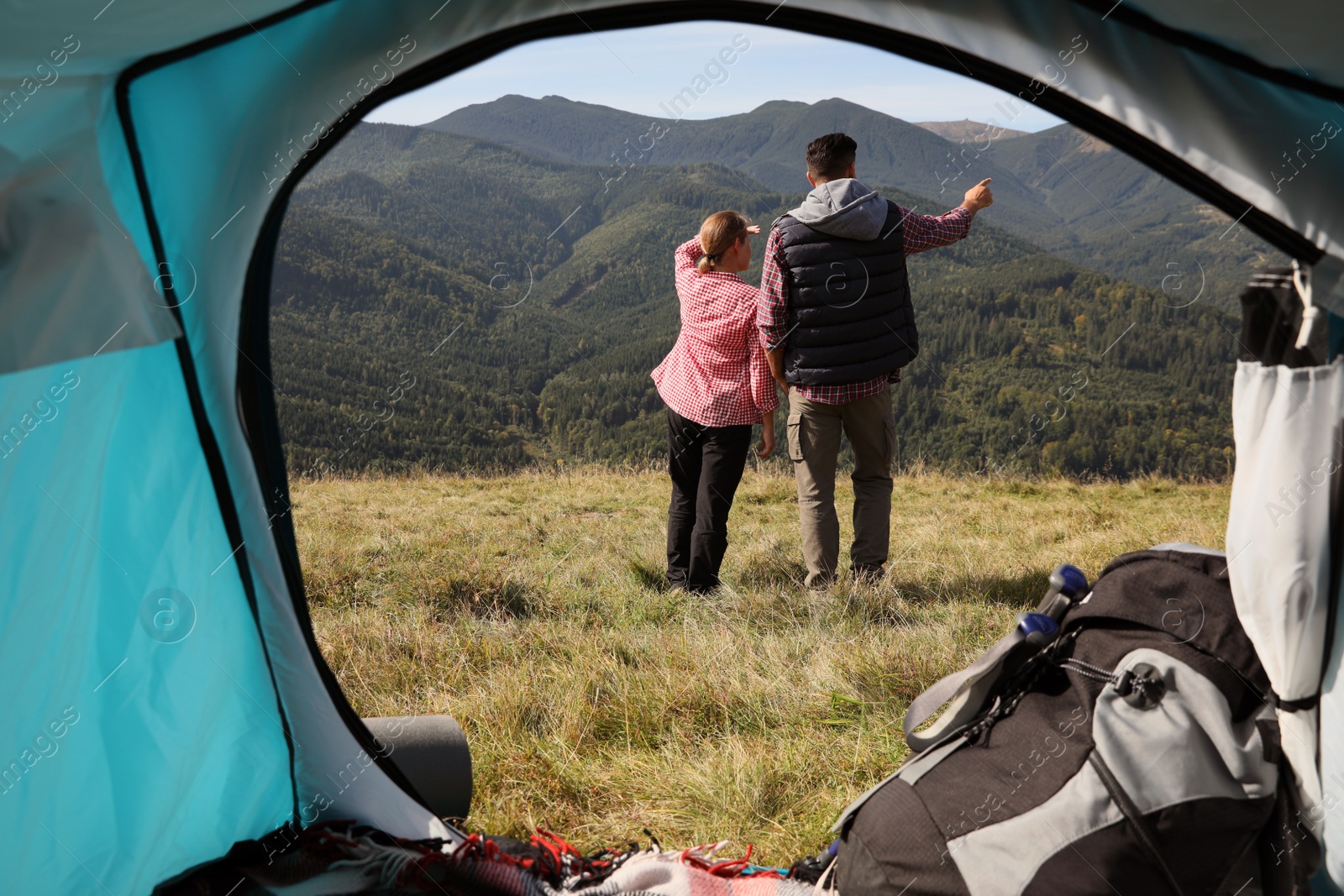 Photo of Couple in mountains on sunny day, view from camping tent