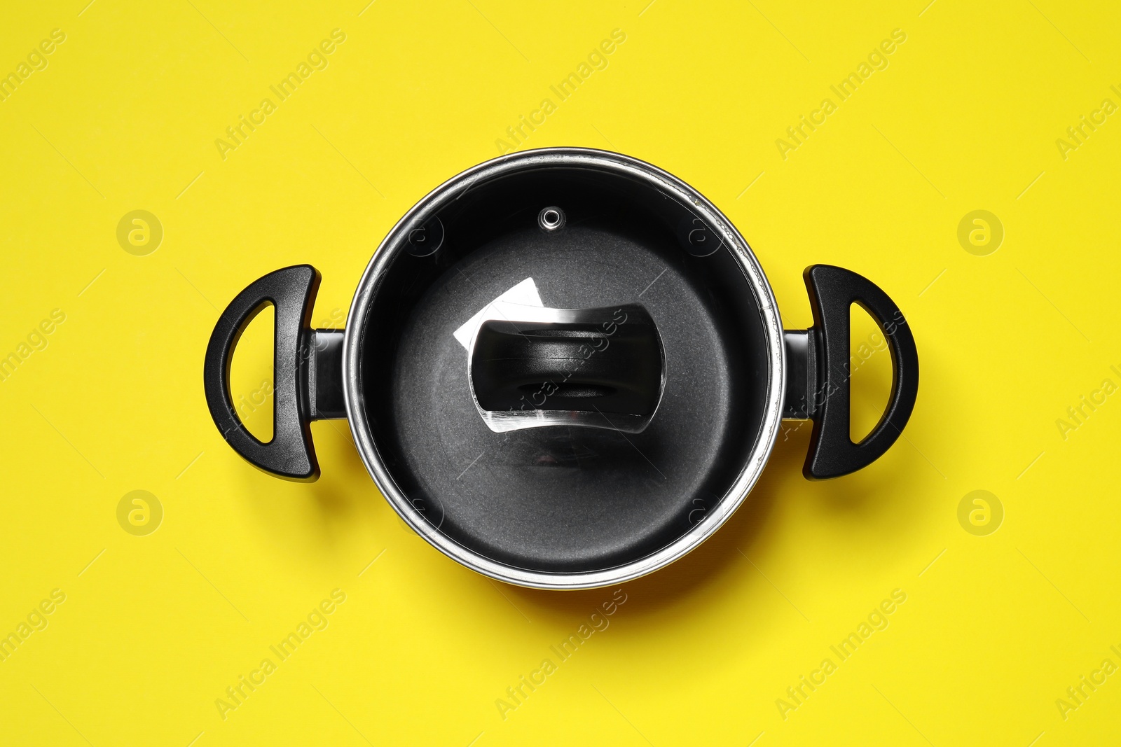 Photo of Empty pot with glass lid on yellow background, top view