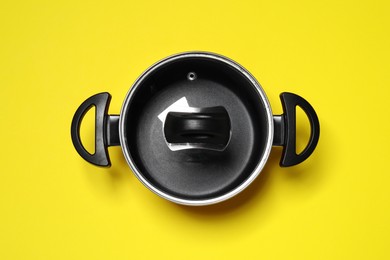 Empty pot with glass lid on yellow background, top view