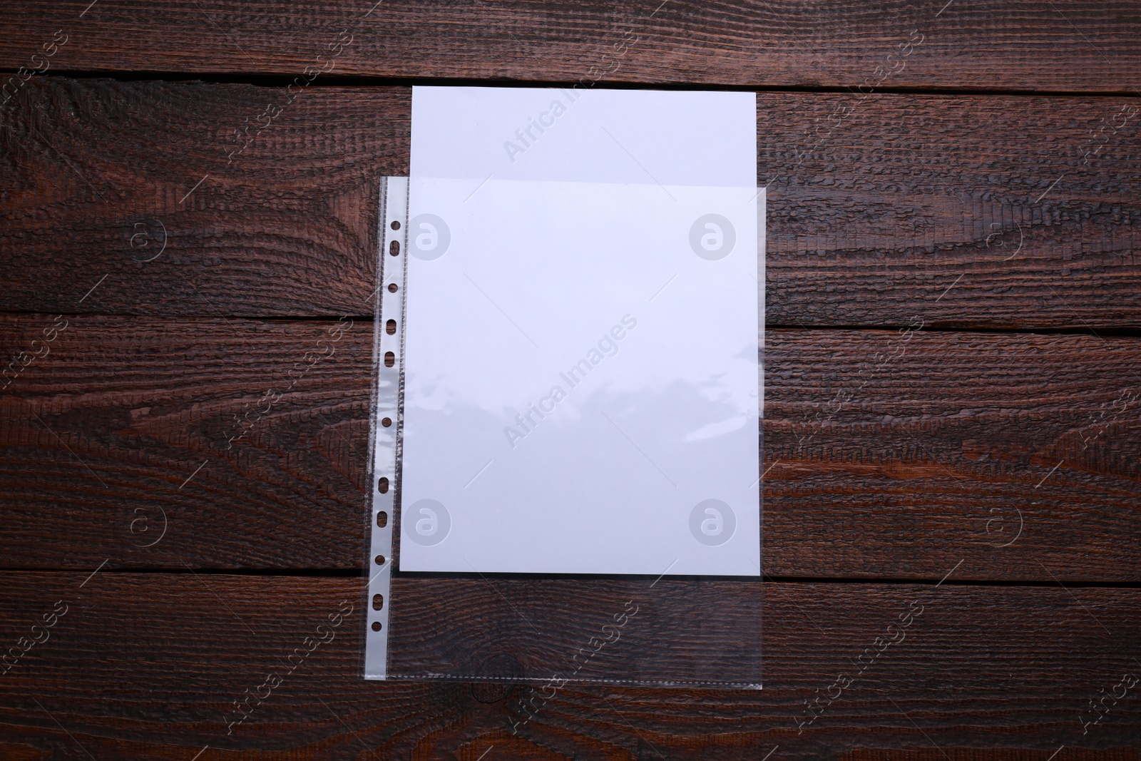 Photo of Punched pocket with paper sheet on wooden table, top view