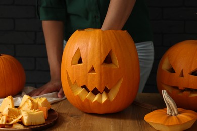 Woman carving pumpkin for Halloween at wooden table, closeup