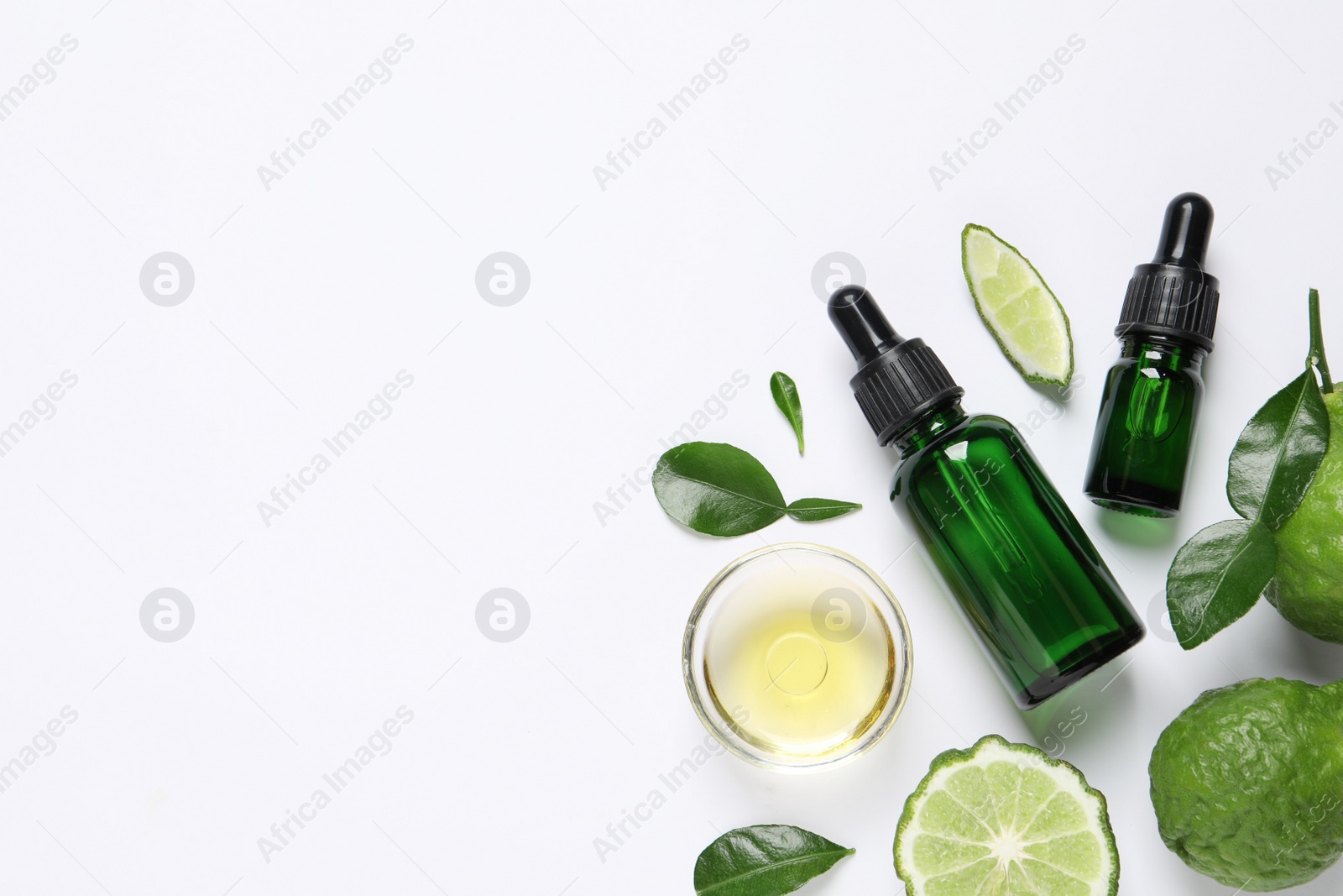 Photo of Bergamot essential oil and fresh fruits on white background, flat lay. Space for text