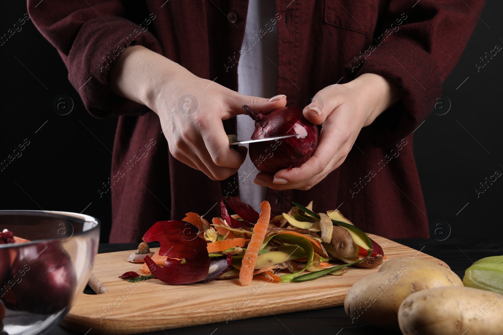 Photo of Woman peeling fresh onion with knife at table, closeup