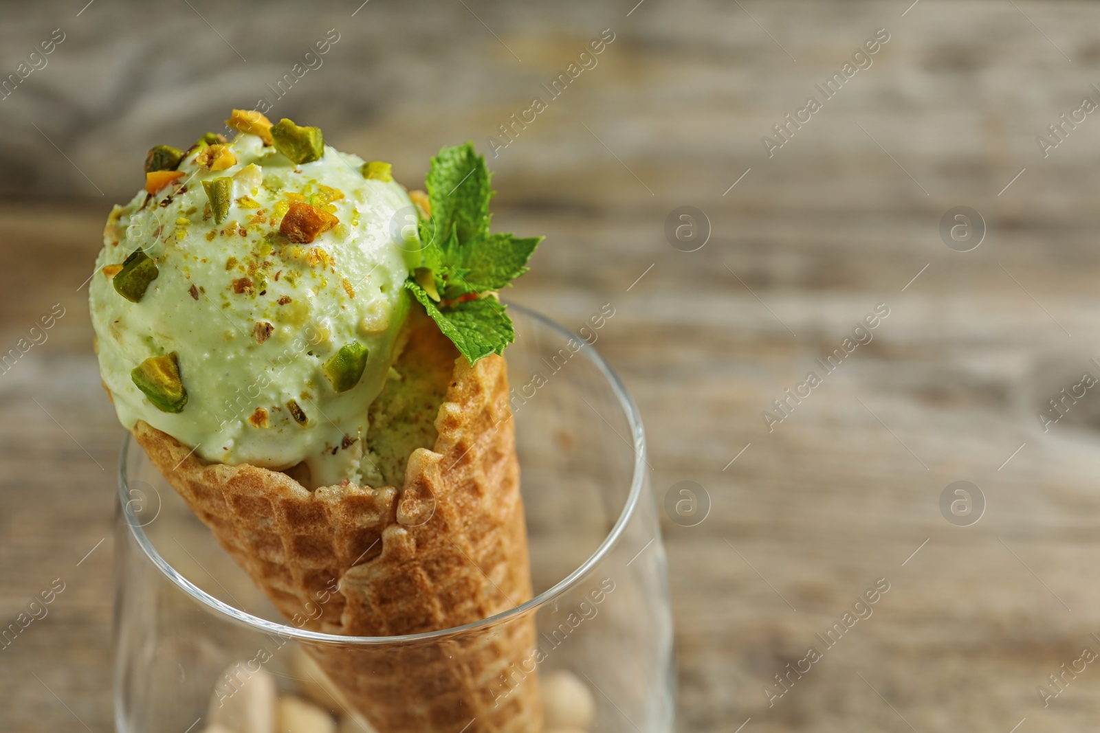 Photo of Delicious green ice cream served on wooden table, closeup. Space for text