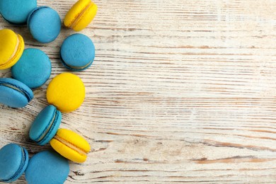 Photo of Delicious colorful macarons on white wooden table, flat lay. Space for text