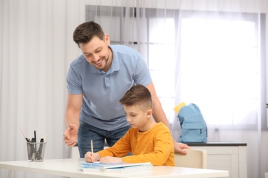 Photo of Dad helping his son with homework in room, space for text
