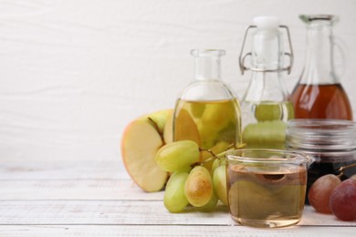 Photo of Different types of vinegar and ingredients on wooden table, closeup. Space for text