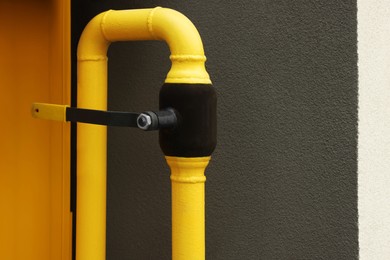 Yellow gas pipe near brown wall outdoors