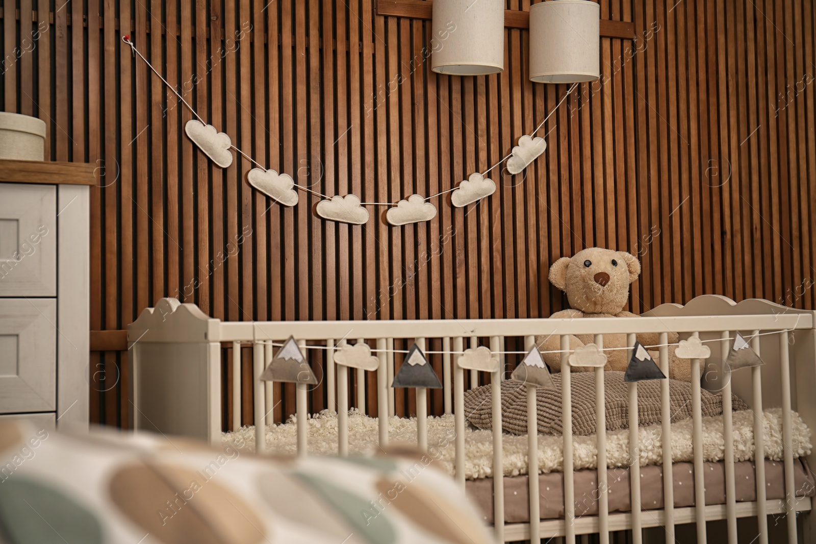 Photo of Baby room interior with crib near wooden wall