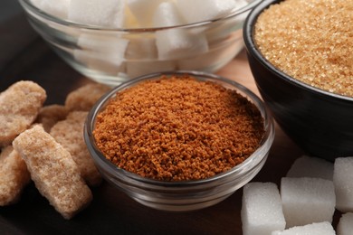 Photo of Different types of sugar on wooden table, closeup