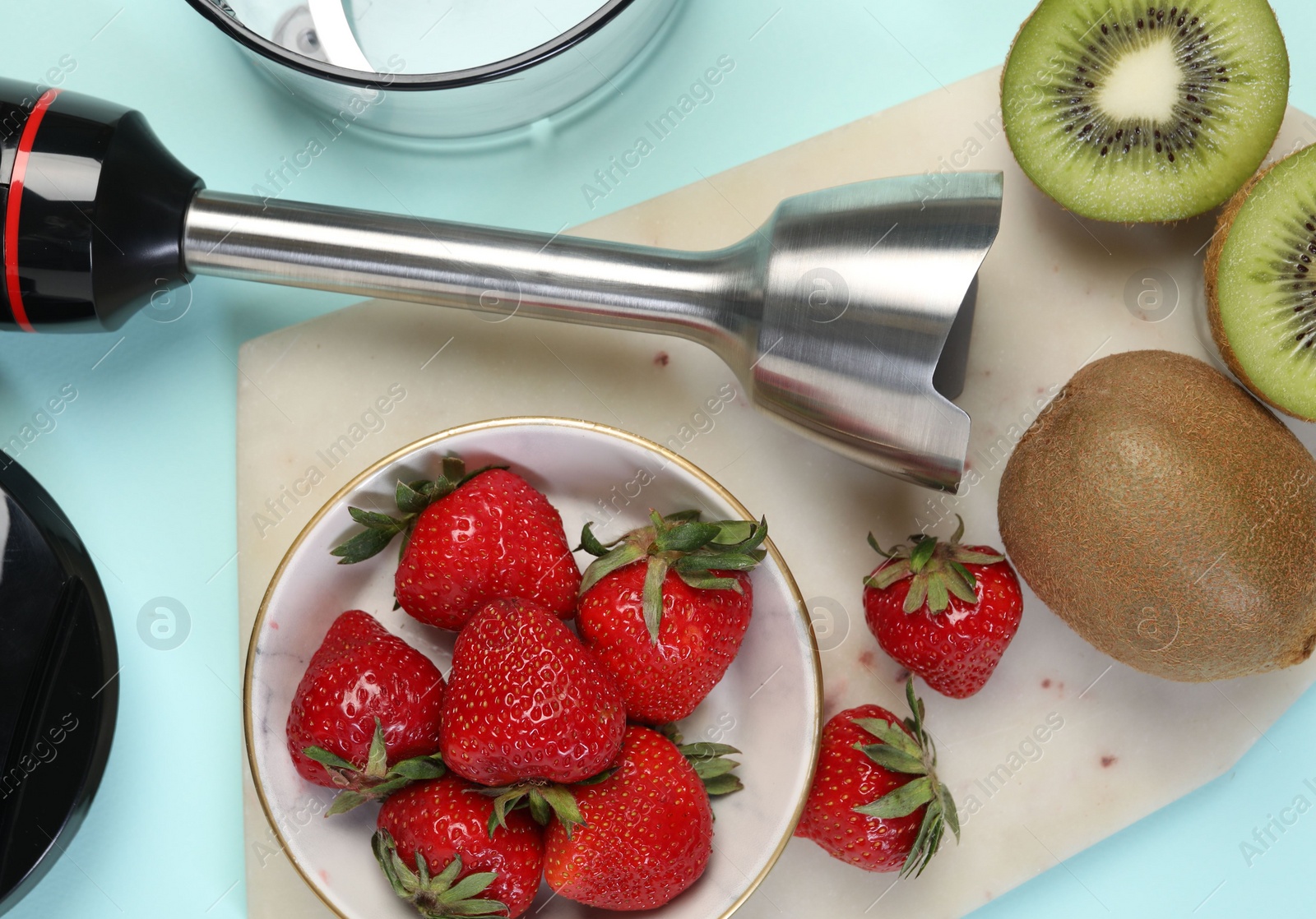 Photo of Hand blender kit and fresh fruits on light blue background, top view