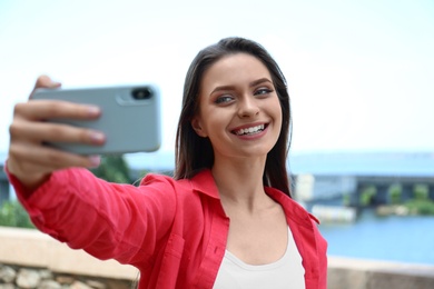 Happy young woman taking selfie on riverside