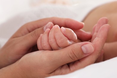 Photo of Mother with her cute baby on bed at home, closeup of hands