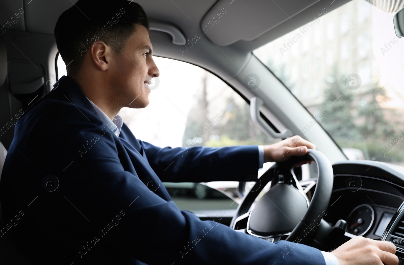 Photo of Handsome man in suit driving his modern car