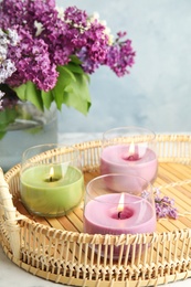 Tray with burning candles and flowers on table, space for text