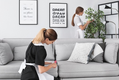 Photo of Professional chambermaids cleaning room in modern hotel