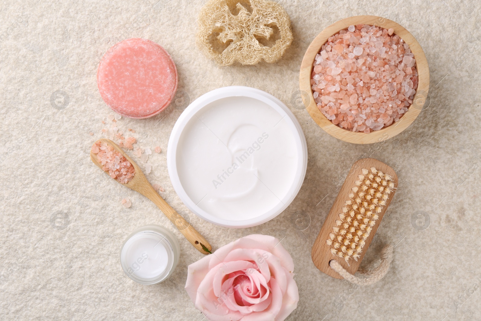 Photo of Flat lay composition with moisturizing cream in open jar and other body care products on light textured table