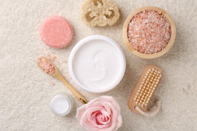 Flat lay composition with moisturizing cream in open jar and other body care products on light textured table