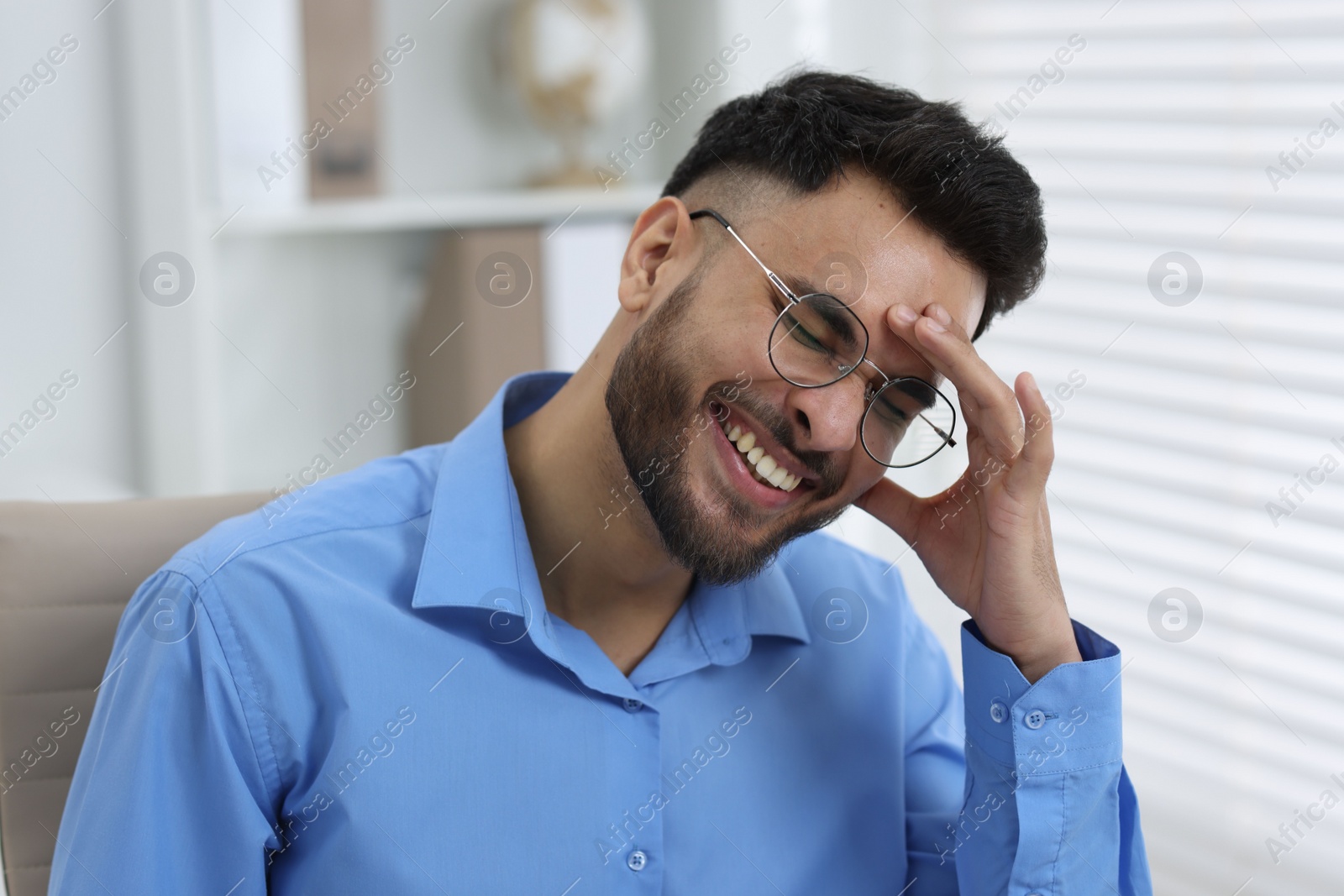 Photo of Portrait of handsome young man laughing in office