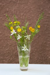 Bouquet of beautiful wildflowers in glass vase on table