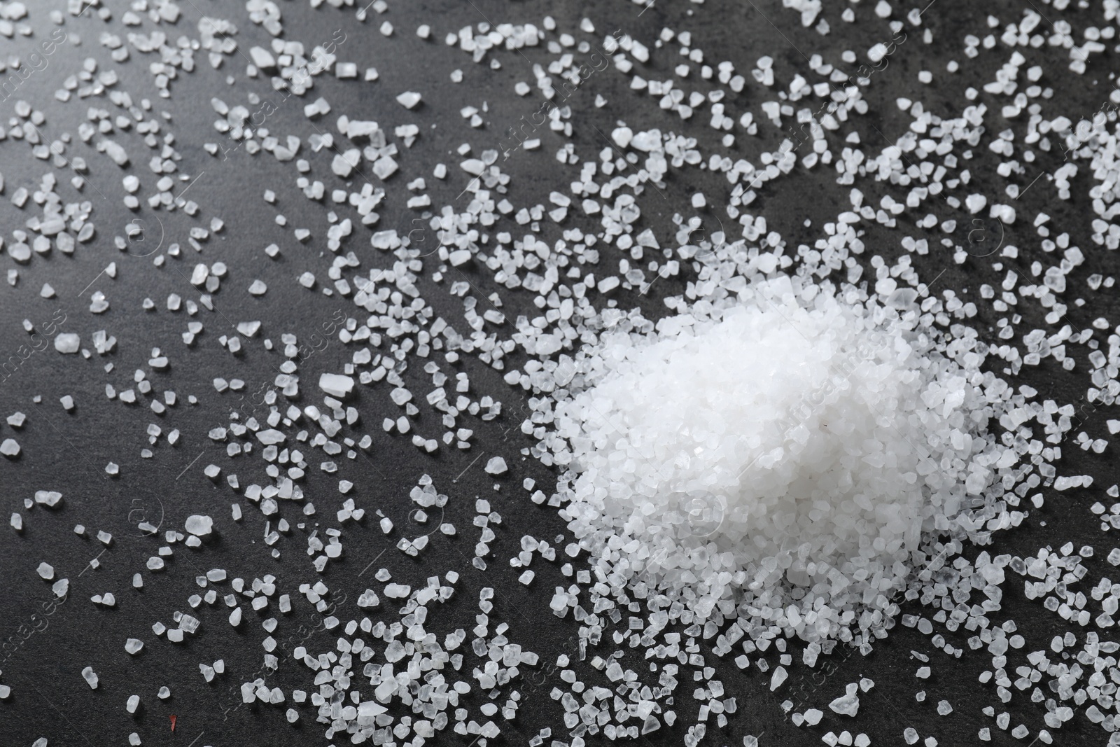 Photo of Heap of natural salt on black table, top view