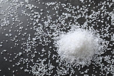 Photo of Heap of natural salt on black table, top view