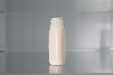 Photo of Bottle of yogurt on shelf inside modern refrigerator