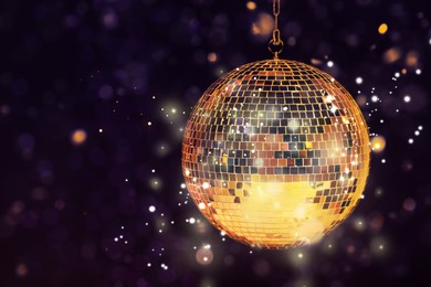 Shiny disco ball on dark purple background with blurred lights, space for text. Bokeh effect
