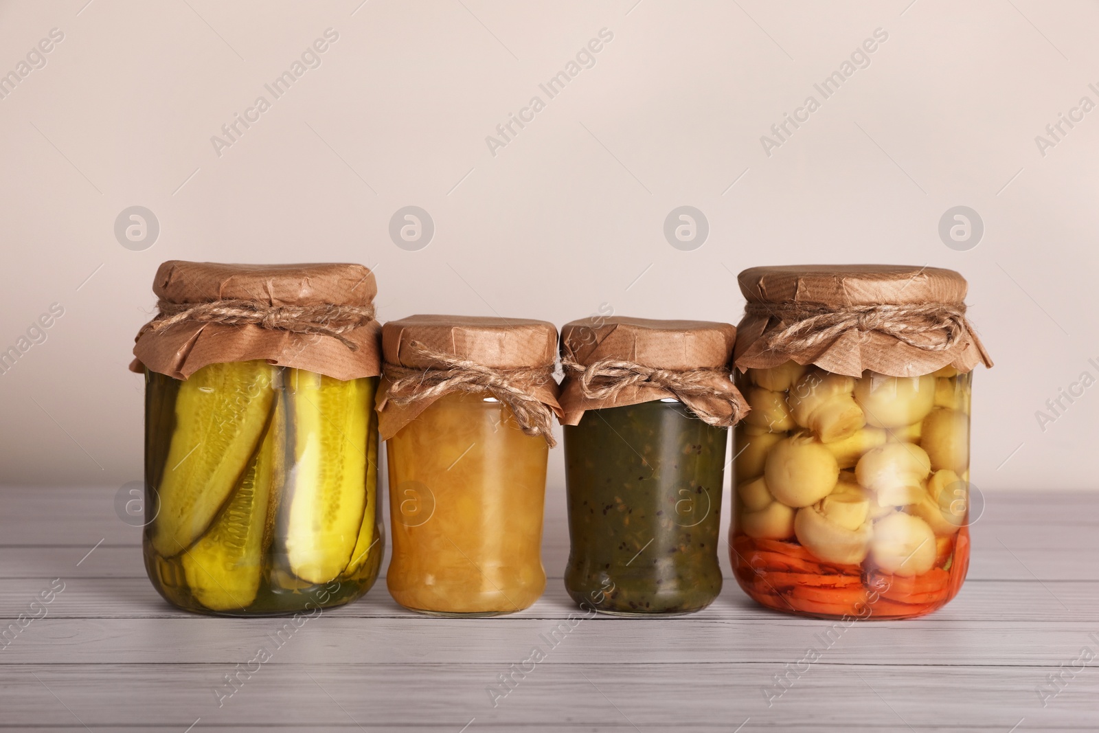 Photo of Jars with different preserved ingredients on wooden table