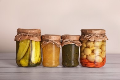 Jars with different preserved ingredients on wooden table