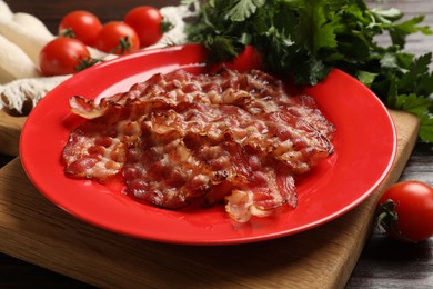 Photo of Plate with fried bacon slices, tomatoes and parsley on table, closeup