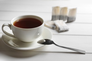 Photo of Tea bags near cup of hot drink on white wooden table. Space for text