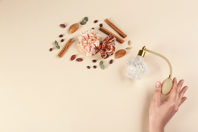 Photo of Woman with perfume. Fragrance composition, flowers and cinnamon on beige background,  top view