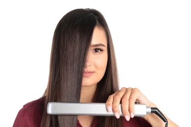 Young woman using hair iron on white background