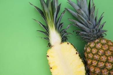 Photo of Whole and cut ripe pineapples on light green background, flat lay. Space for text