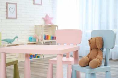 Photo of Cozy kids room interior with table, chairs and toy rabbit