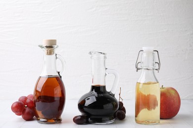 Photo of Different types of vinegar and ingredients on light tiled table, closeup