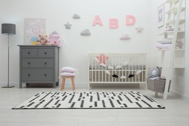 Cute baby room interior with crib and chest of drawers near white wall