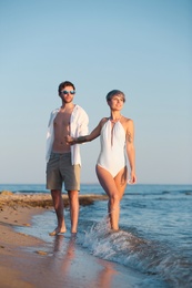 Happy young couple walking together on beach