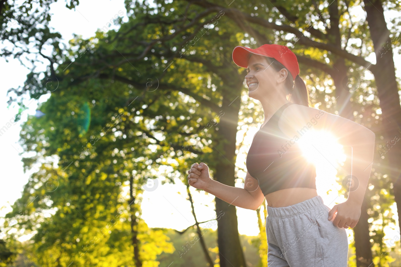 Photo of Young woman running outdoors in morning, low angle view. Space for text